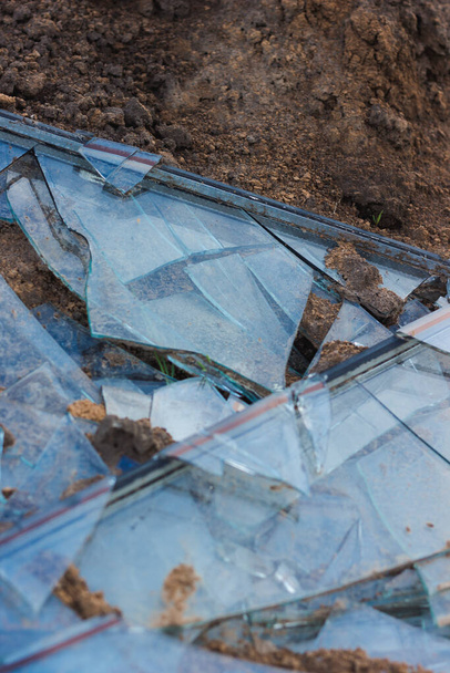 Ένα σπασμένο παράθυρο στο έδαφος. Σπασμένο γυαλί. Θραύσματα. - Φωτογραφία, εικόνα