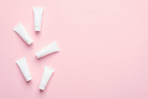 Blank white cosmetic tubes on pink background. Packaging cream containers design. Flat lay, top view. - Φωτογραφία, εικόνα