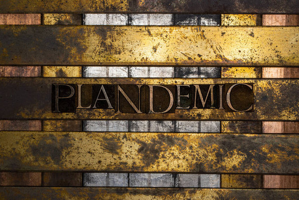 Photo of real authentic typeset letters forming Plandemic text on vintage textured silver grunge copper and gold background - Photo, Image