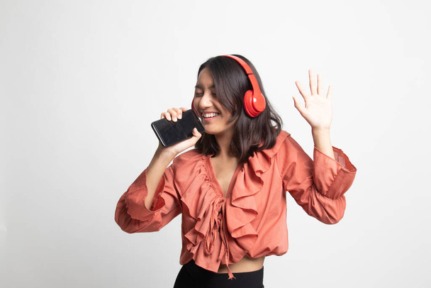 Güzel Asyalı kız beyaz arka planda kulaklıklarıyla müzik dinliyor. - Fotoğraf, Görsel