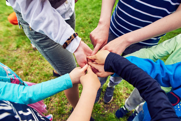 Kinderen teambuilding. Onderwijs, kinderen, het concept van mensen - een groep gelukkige kinderen die elkaars hand vasthouden. team outdoor in park of speeltuin. - Foto, afbeelding