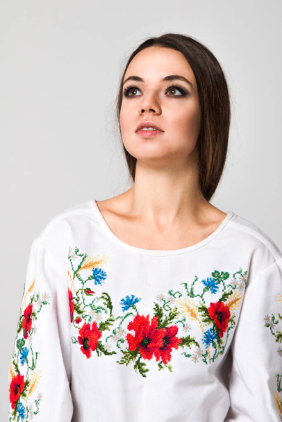 emotional girl on a white background, Girl in the national Ukrainian embroidered shirt on a white background. Beauty, homeland, emotion, stylized costume, modern, symbol, costumes, red, traditions. - Фото, изображение