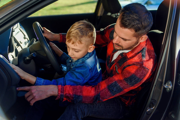 handsome father pointing on something while teaching teen son driving car - Φωτογραφία, εικόνα