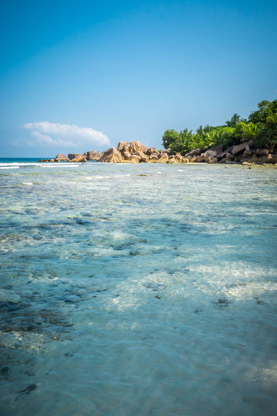 portré formátum szép trópusi homokos strand híres gránit sziklák Anse Coco strand, La Digue Island, Seychelles. Nyaralás és nyaralás koncepció. Trópusi strand a háttér kék ég - Fotó, kép