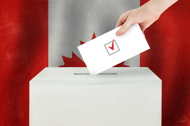 Концепция канадского голосования. Рука избирателя держит бюллетень для голосования на избирательном участке
 - Фото, изображение