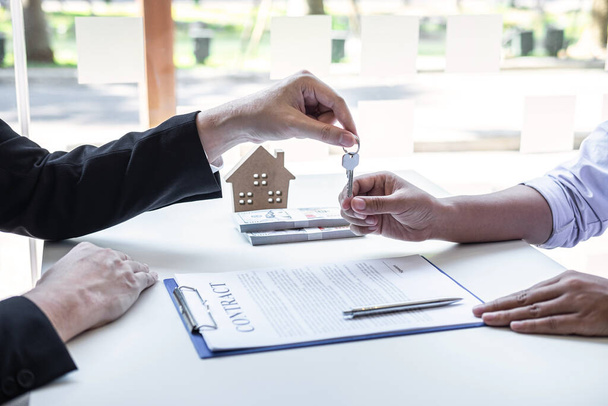 Agente inmobiliario que da llaves de la casa al cliente después de firmar contrato de contrato de bienes raíces con el formulario de solicitud de hipoteca aprobado, en relación con la oferta de préstamo hipotecario y seguro de la casa. - Foto, imagen
