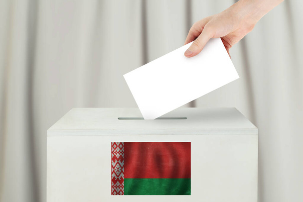 Концепция белорусского голосования. Рука избирателя держит бюллетень для голосования на избирательном участке
 - Фото, изображение