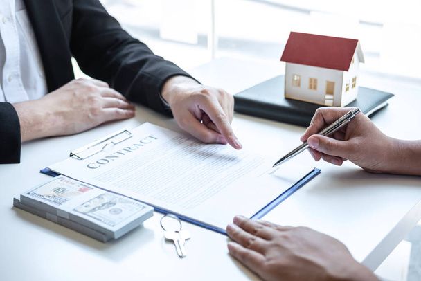 pośrednik w obrocie nieruchomościami wskazujący formularz umowy klientowi podpisującemu umowę o nieruchomość z zatwierdzonym formularzem wniosku o kredyt hipoteczny, kupujący lub dotyczący oferty kredytu hipotecznego i ubezpieczenia mieszkaniowego. - Zdjęcie, obraz