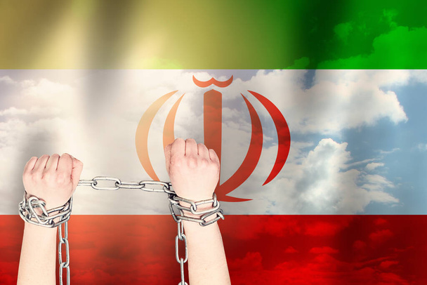 Two hands shackled a metal chain on the background of the Iran flag. Freedom concept - Photo, Image