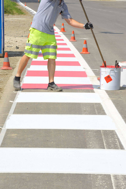 worker painting red and white  road markings on the street - Photo, Image