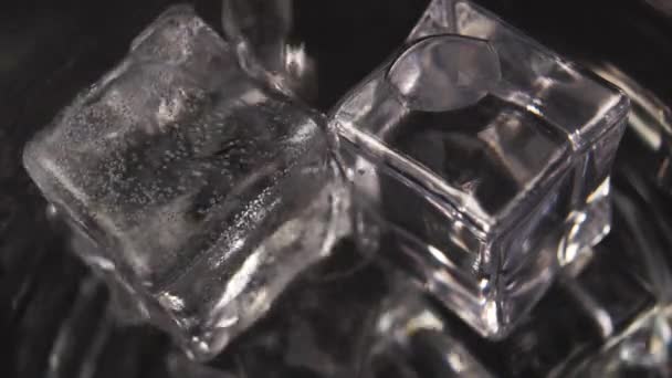 Mineral karbonat suyu, bir sürü köpüklü baloncuğun yakın çekim oluşturduğu bir bardakta buz küplerine dökülür. Makro çekim - Video, Çekim