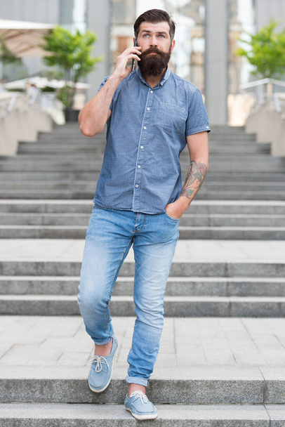 Casual conversation. Hipster in casual style urban outdoor. Bearded man talk on mobile phone. Casual fashion trends. Fashion and style. Everyday wear. Casual menswear store. Modern life - Photo, Image