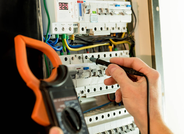 The man is repairing the switchboard voltage with automatic switches. - Foto, Imagen