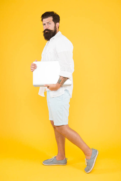 His style is a lot more casual. Bearded man in casual hipster style. Hipster hold laptop yellow background. Casual wear. Fashion blog. Mens style. Its casual enough - Fotó, kép