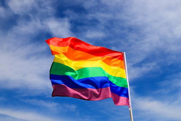 Ρεαλιστική σημαία ουράνιου τόξου ενός ΛΟΑΤ οργανισμού που κυματίζει στον ουρανό. Σημαίες υπερηφάνειας ΛΟΑΤ περιλαμβάνουν λεσβίες, ομοφυλόφιλους, αμφιφυλόφιλους και τρανσέξουαλ. - Φωτογραφία, εικόνα
