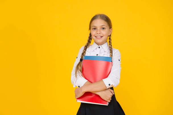 Courses for gifted children. Basic level. Happy schoolgirl hold textbooks yellow background. Little schoolgirl back to school. Small schoolgirl wear uniform. Cute schoolgirl. School education - Photo, Image