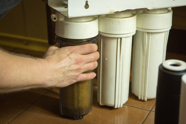 El maestro reemplaza los filtros sucios en el sistema de purificación de agua del hogar. Manos humanas, filtro, membrana
. - Foto, Imagen