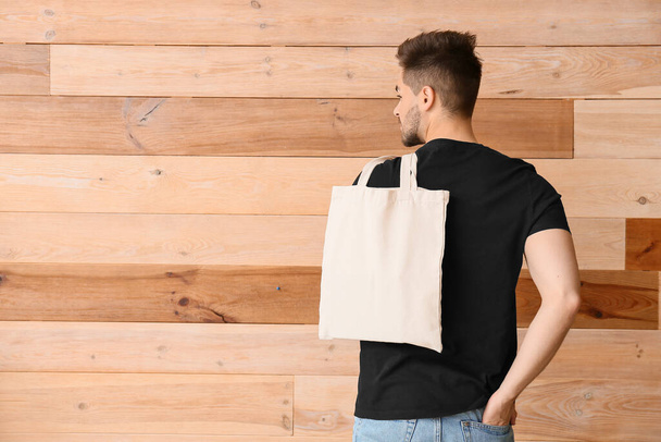 Młody człowiek z eko torbą na drewnianym tle - Zdjęcie, obraz