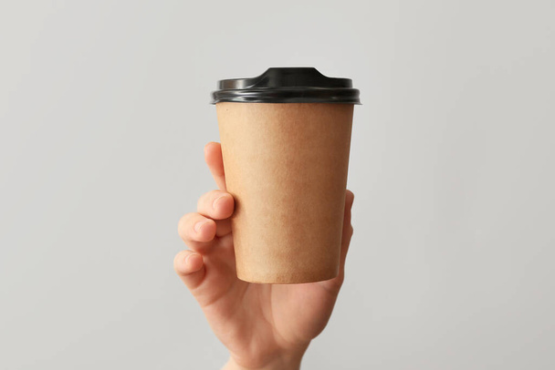 Mano femenina con taza de café sobre fondo gris
 - Foto, Imagen