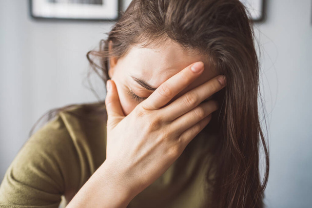 Tired young female touching forehead having headache migraine or depression. - Фото, зображення