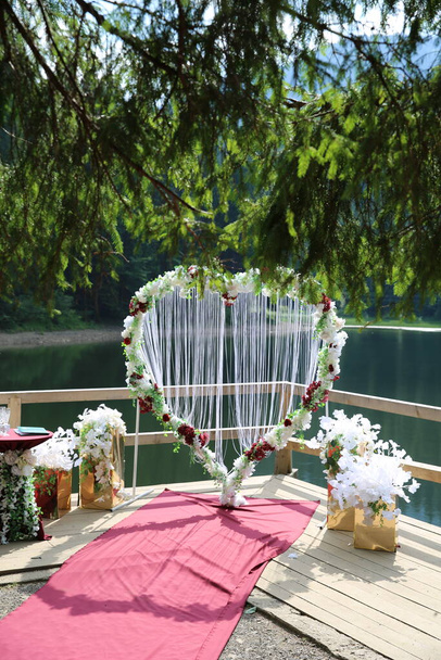 Hart met bloemen op een houten boot in de buurt van een meer in de bergen en bos en bruiloft - Foto, afbeelding