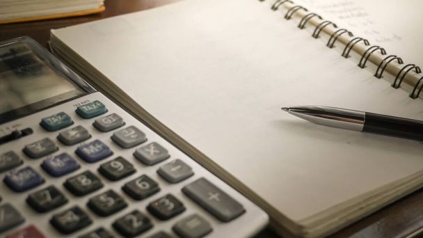 una pluma en un cuaderno con una calculadora
 - Foto, Imagen