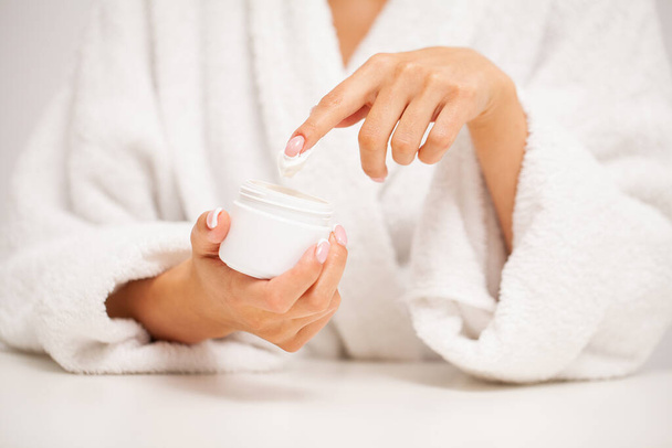 Woman applies moisturizer cream for hand skin care - Фото, изображение
