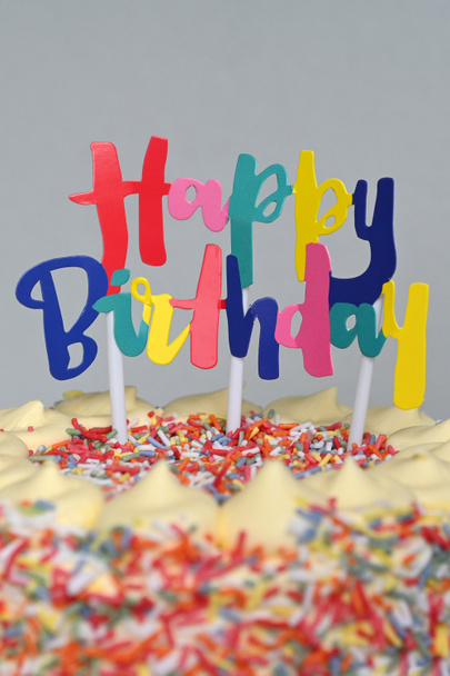 Feliz sinal de aniversário em cima de um bolo de arco-íris servido na festa de aniversário tema arco-íris
. - Foto, Imagem