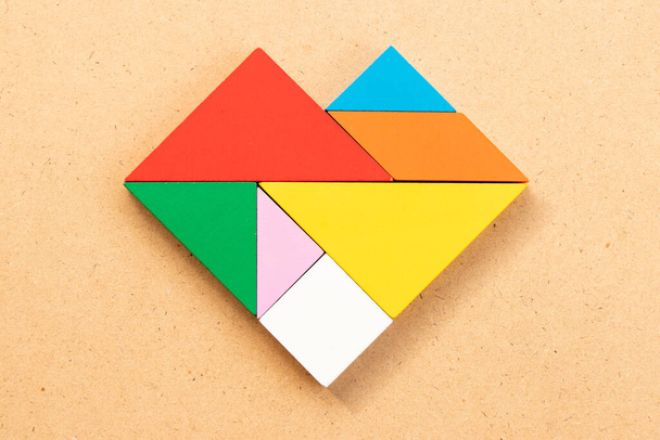 Kleur tangram puzzel in hartvorm op hout bacground - Foto, afbeelding