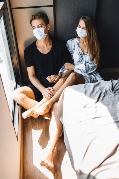 男と女が顔にマスクで床に座っている - 写真・画像