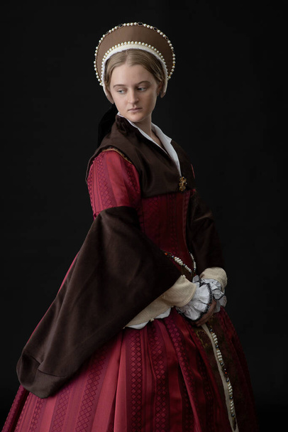 Tudor nainen punainen ja ruskea puku seisoo mustaa taustaa vasten - Valokuva, kuva