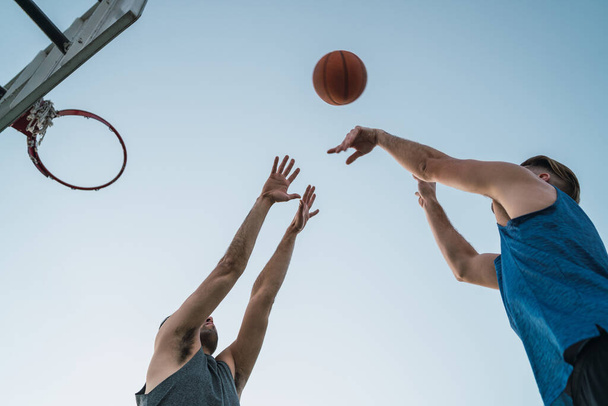 Young basketball players playing one-on-one on outdoor court. Sport and basketball concept. - Photo, Image