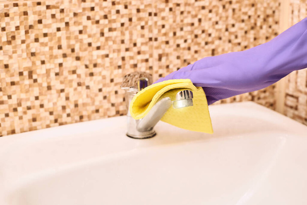 House worker clean bathroom. Purple glove with yellow rag - Zdjęcie, obraz