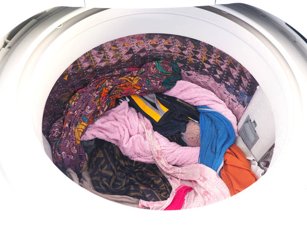 Vista superior de la lavadora blanca con ropa después de girar cargada en el interior
. - Foto, Imagen