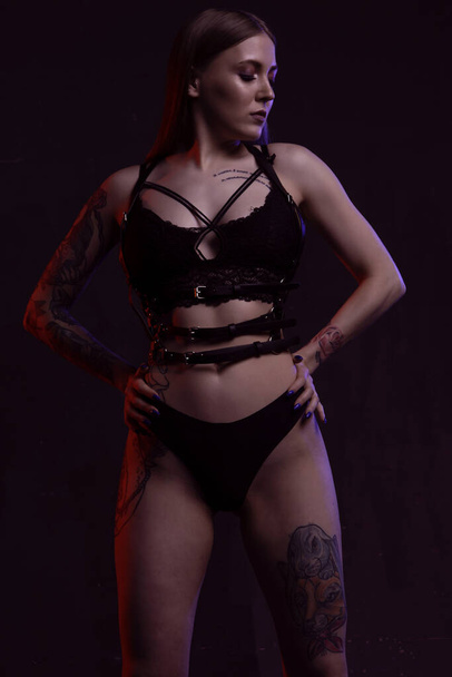 sexy girl with perfect body in underwear and leather holster on dark background - Valokuva, kuva