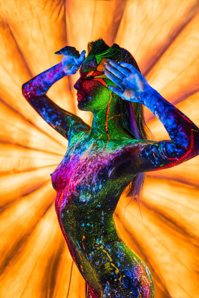 Girl with ultraviolet bodyart posing topless against bright umbrella - Foto, Imagem