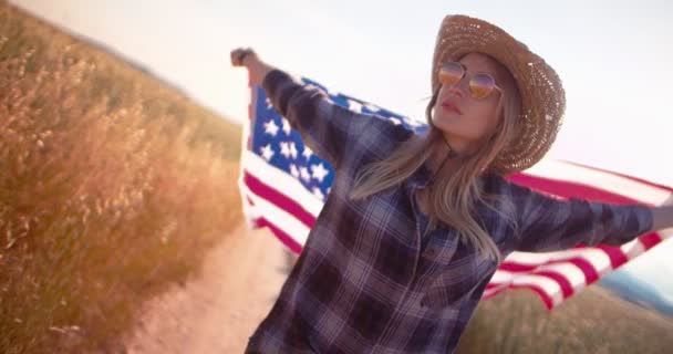 American woman with flag on road trip in the countryside - Záběry, video
