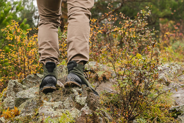 Hiking boots on rock. Mens feet in boots on natural stones. Travel and adventure concept - Photo, Image