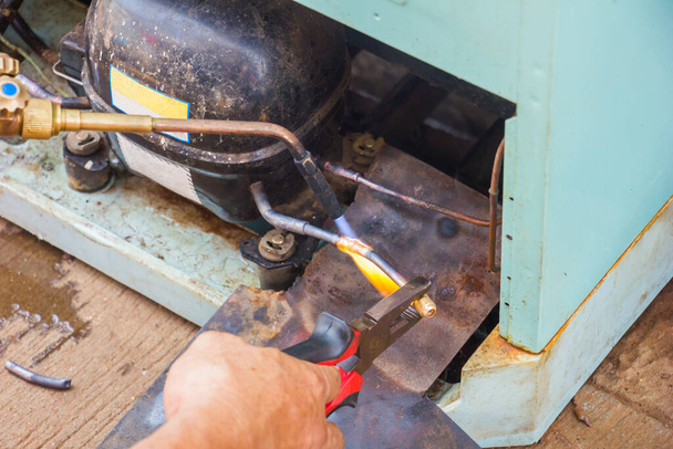 réparer le vieux travail de réfrigérateur, technicien soudant le tuyau de cuivre par le gaz avant le système de vide à l'atelier de maintenance
. - Photo, image