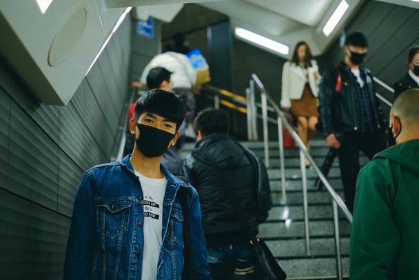 Mies käyttää suojaavaa kasvonaamiota metroasemalla muiden ihmisten kanssa viruksen suojelemiseksi. Covid-19 suojaus käsite, kun mennä ulos julkisilla paikoilla - Valokuva, kuva
