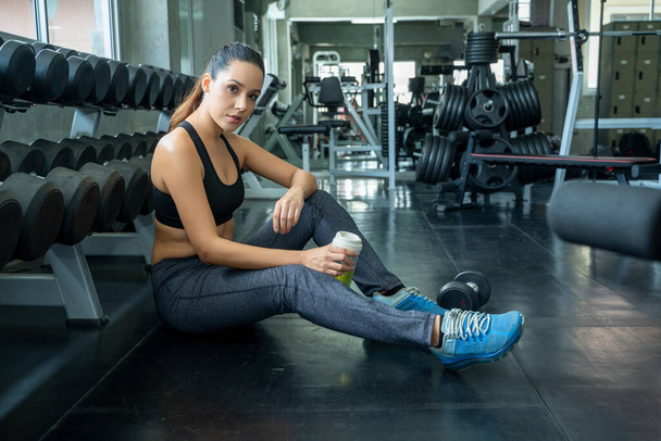 Athletic woman resting after work out exercise in modern fitness club gym. - Foto, Imagen