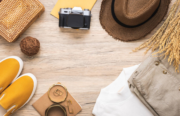summer travel flat lay of traveller accessories set.cloth,hat,wicker bag,canvas shoe,camera and notebook on wooden table with copy space - Foto, Imagem