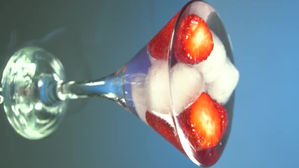 Macro of a professional bartender is putting professional crystal ice cubes in a glass while preparing an alcoholic cocktail to customers at the bar or disco club. Vertical video for smartphones and tablets - Footage, Video