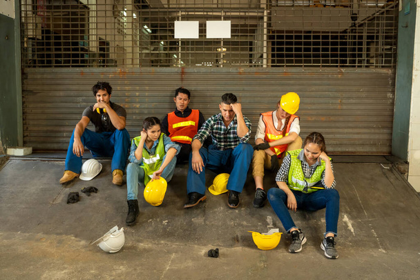 Grupo de Ingenieros desempleados de la empresa sentados tristes en fábrica Después de recibir noticias sobre cierres de fábricas debido a la enfermedad por Coronavirus 2019 (COVID-19
). - Foto, Imagen