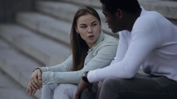 Two multiracial friends talking sitting in a city - Video, Çekim