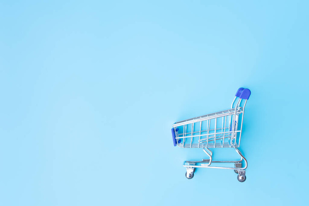 Shopping cart on blue background with copy space. Shopping concept - Photo, image