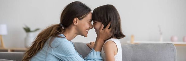Любящая мать трогает носы с очаровательной маленькой дочерью вид сбоку
 - Фото, изображение