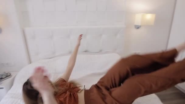 Radosna kobieta w piżamie upadająca na łóżko - Materiał filmowy, wideo