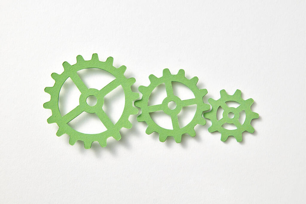 Set of papercraft machine gear different size handmade from green color paper on a white background with shadows, copy space. Top view. - Photo, image
