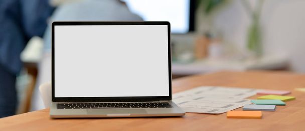 Close-up weergave van UI ontwikkelaar werkruimte met blanco scherm laptop, papierwerk en notitieblok op houten bureau  - Foto, afbeelding